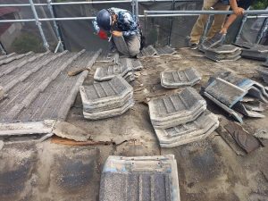 セメント瓦を一枚ずつ手作業で解体している作業員