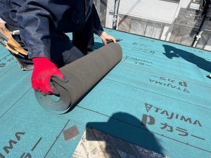 作業員がルーフィングを敷いているところ