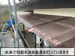 水糸で勾配を決めて波板に金具を打っている様子
