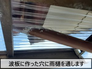 波板に作った穴に雨樋を通している様子